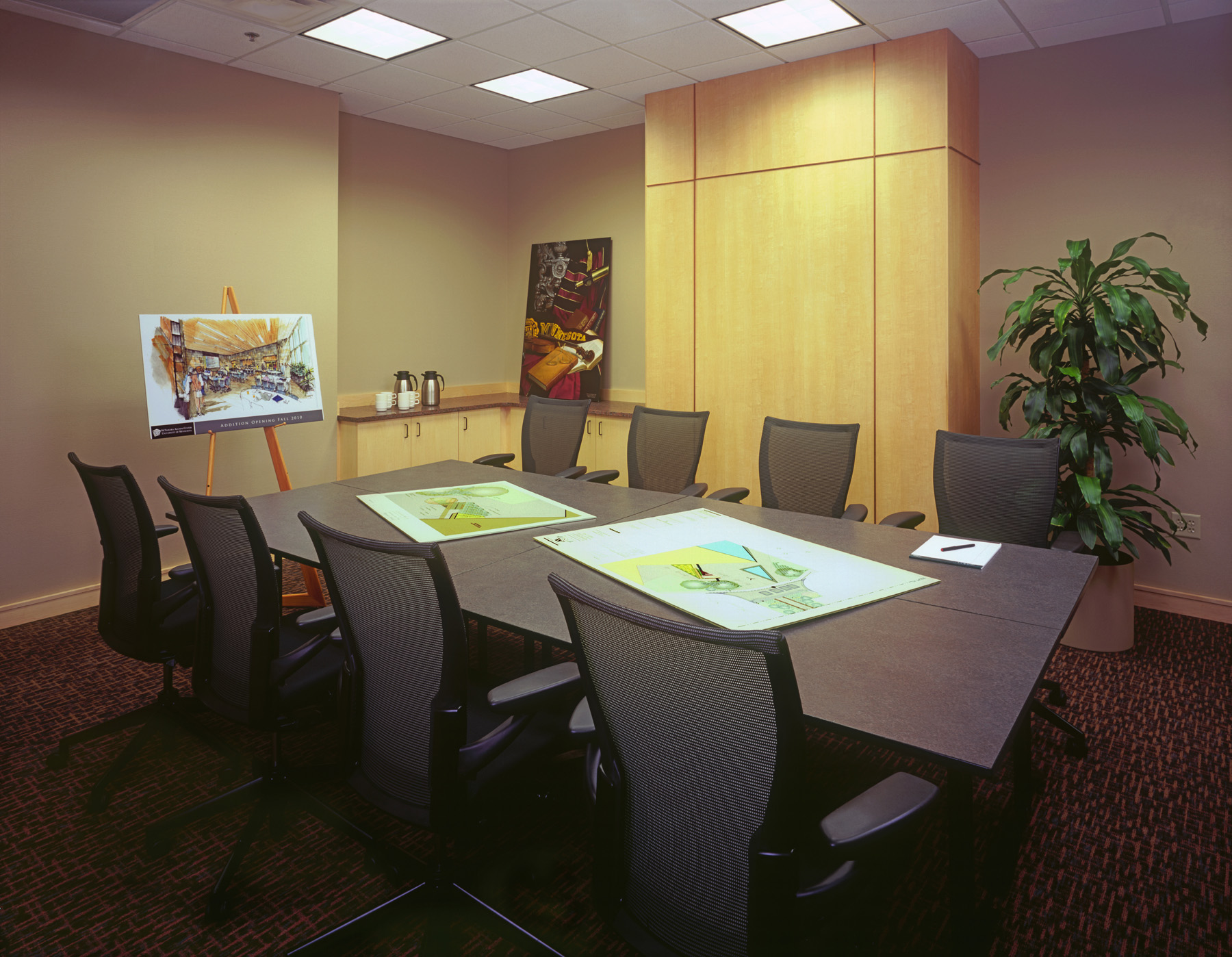 A small conference room with a table in the center, there are 8 chairs around it.